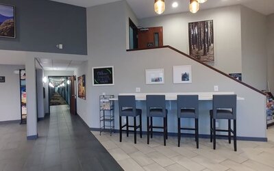 Hotel lobby seating area with upholstered chairs and sofas, large windows, coffee tables, and contemporary decor at Garner by IHG.