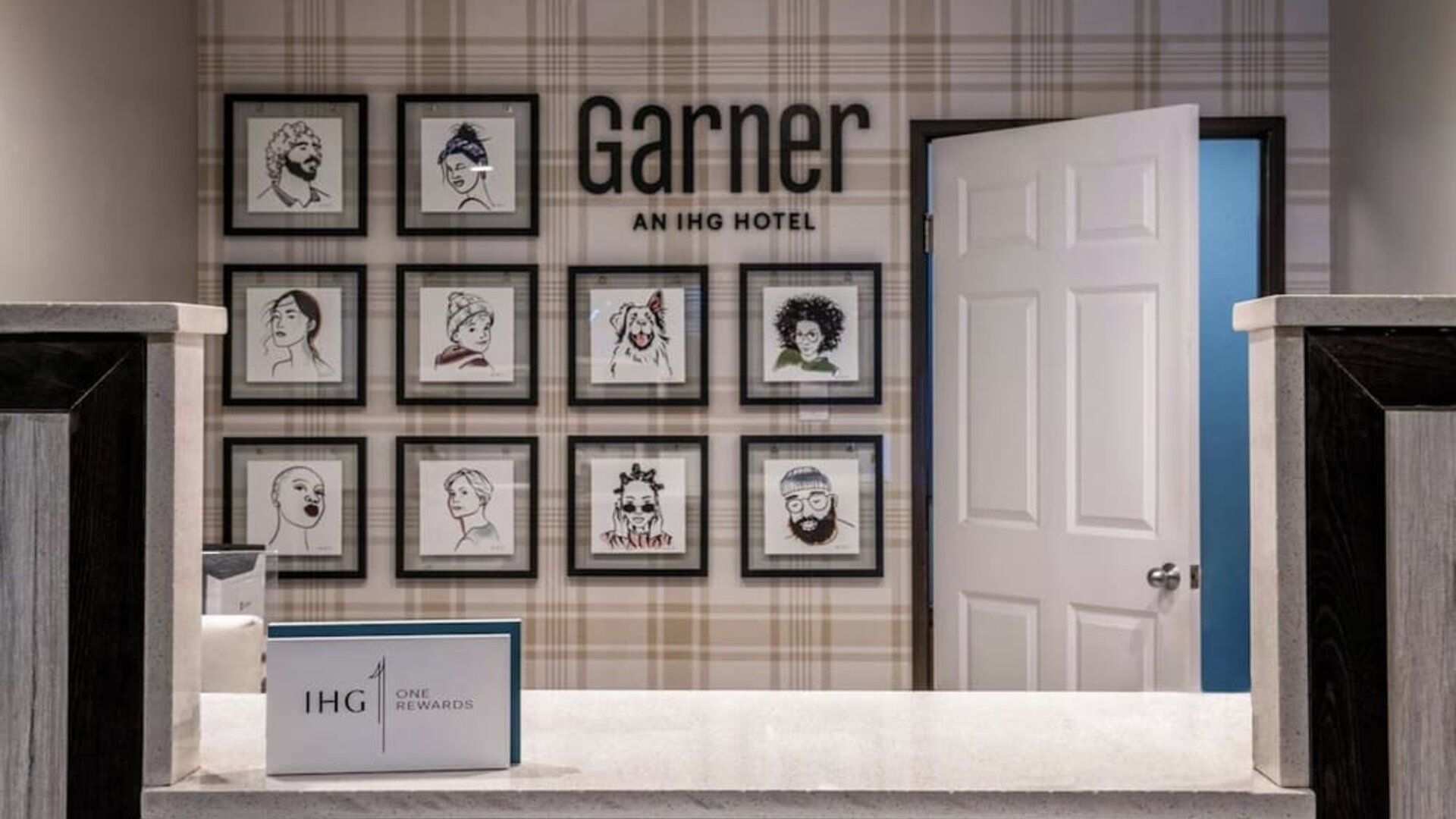 Reception area with a front desk, framed artwork, Garner branding, and IHG One Rewards signage at Garner by IHG.