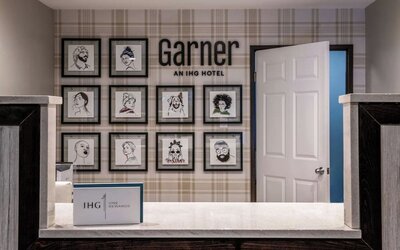 Reception area with a front desk, framed artwork, Garner branding, and IHG One Rewards signage at Garner by IHG.