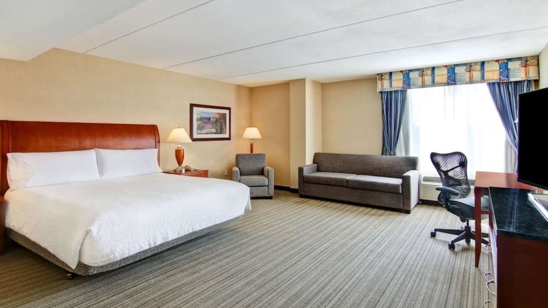 Day use room with TV, work desk, and sofa at Hilton Garden Inn Toronto/Burlington.