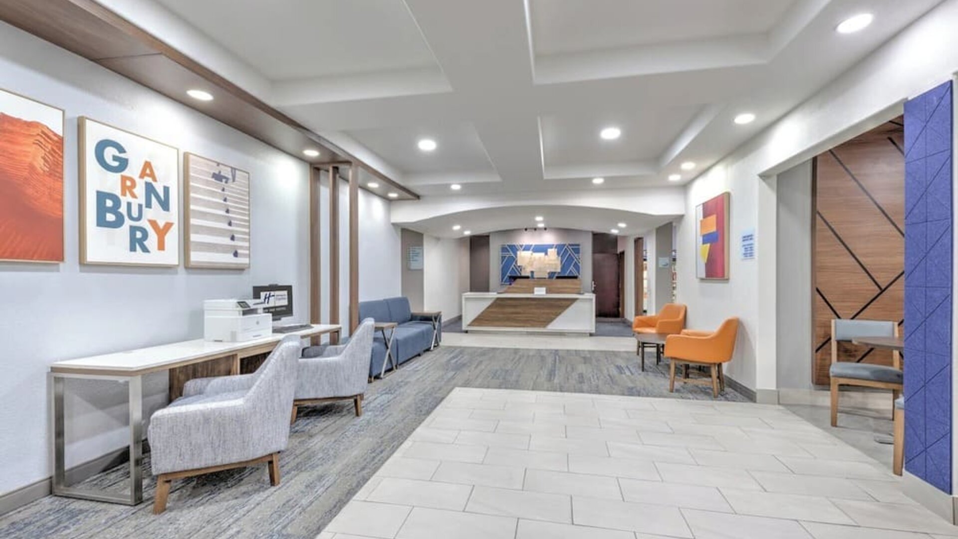 Hotel lobby and reception area with modern seating, colorful artwork, wood accents, and a front desk at Holiday Inn Express & Suites Granbury.