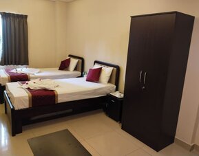 Twin bed hotel room featuring white bedding, burgundy accents, decorative towel arrangements, dark wooden furniture, a spacious wardrobe, and tiled flooring.