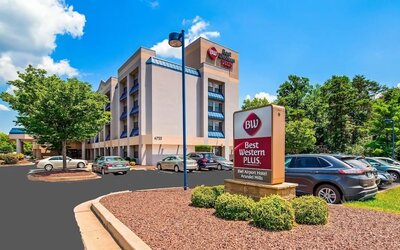 Exterior view of Best Western Plus BWI Airport Arundel Mills, showing the hotel building, branded roadside sign, landscaped grounds, and parking area in daylight.