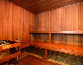 Wooden sauna room with timber walls, built-in benches, and an electric sauna heater at Best Western Plus BWI Airport Arundel Mills.