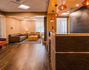 Reception lounge featuring a front desk, comfortable seating, warm wood flooring, pendant lighting, and contemporary wall decor at Best Western Plus BWI Airport Arundel Mills.