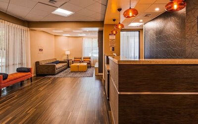 Reception lounge featuring a front desk, comfortable seating, warm wood flooring, pendant lighting, and contemporary wall decor at Best Western Plus BWI Airport Arundel Mills.