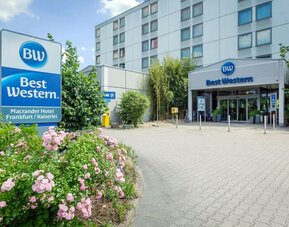 The exterior of Best Western Macrander Hotel Frankfurt/Kaiserlei, showcasing its multi-storey modern building, clearly branded entrance, paved forecourt, parking area and landscaped flower beds.
