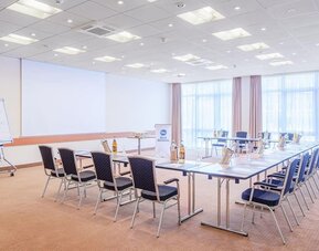 A meeting room configured in a boardroom-style layout, with tables arranged in a rectangular formation, conference chairs, presentation equipment, a flip chart and large windows providing natural light.A recreational area featuring a black foosball table 