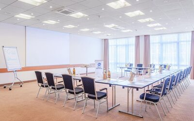 A meeting room configured in a boardroom-style layout, with tables arranged in a rectangular formation, conference chairs, presentation equipment, a flip chart and large windows providing natural light.A recreational area featuring a black foosball table 