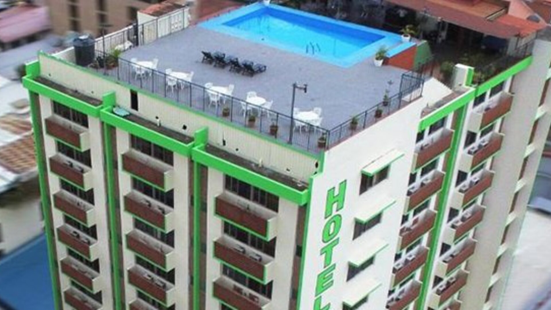 Multi-storey hotel exterior with green trim, rows of balconies and a rooftop swimming pool at Caribe Panamá Hotel.