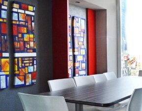 Meeting room with a long conference table, white chairs, colourful geometric wall art and large windows overlooking the city at Hotel Block Suites.