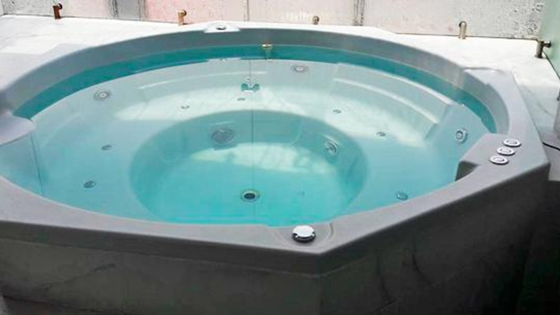 Indoor whirlpool bath with turquoise water, built-in seating and tiled surround at Hotel Block Suites.