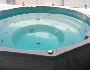 Indoor whirlpool bath with turquoise water, built-in seating and tiled surround at Hotel Block Suites.