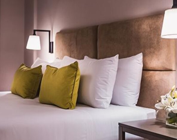 1. Guest room with a king-size bed, white bedding, olive-green accent cushions, upholstered headboard and bedside lighting at Howard Johnson Plaza Buenos Aires.