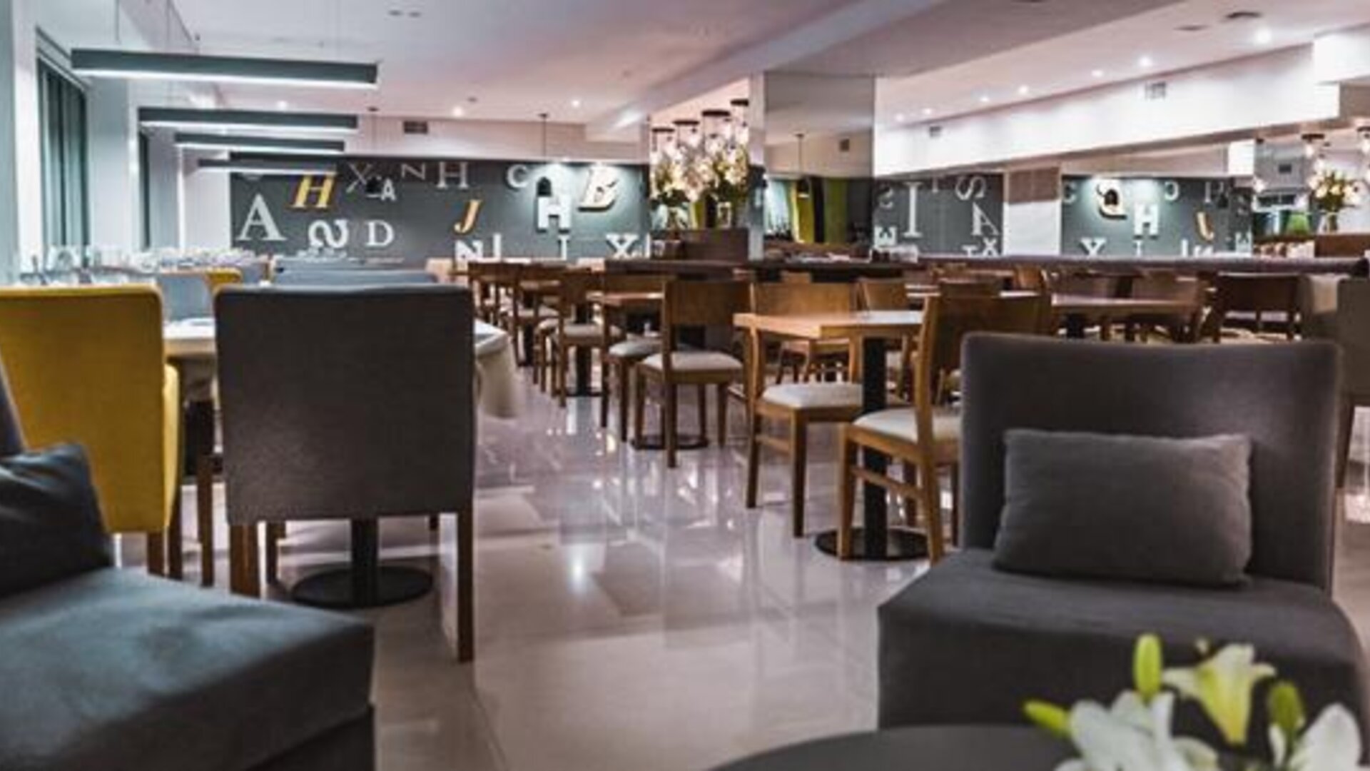 Dining area with tables, upholstered chairs, pendant lighting and polished floors at Howard Johnson Plaza Buenos Aires.