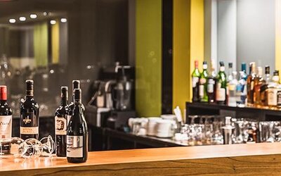 Hotel bar with wine bottles, glassware, a wooden counter and illuminated shelving at Howard Johnson Plaza Buenos Aires.