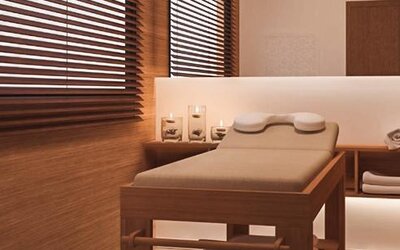 Spa treatment room with a padded massage table, folded towels, candles and warm wood-panelled walls at Howard Johnson Plaza Buenos Aires.