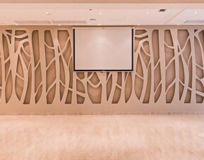 Conference room with decorative geometric wall panels, projection screen and polished flooring at Howard Johnson Plaza Buenos Aires.