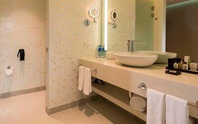 Modern bathroom with a walk-in shower, twin vessel sinks, large mirrors and folded towels at Hotel Las Américas Golden Tower Panamá.