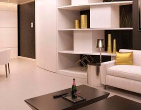Modern hotel suite lounge with cream sofas, gold accent cushions, a coffee table and built-in shelving at Hotel Las Américas Golden Tower Panamá.