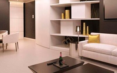 Modern hotel suite lounge with cream sofas, gold accent cushions, a coffee table and built-in shelving at Hotel Las Américas Golden Tower Panamá.