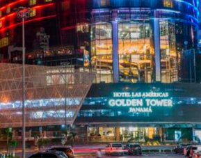 Night-time exterior of Hotel Las Américas Golden Tower Panamá, featuring illuminated glass architecture and colourful building lights.