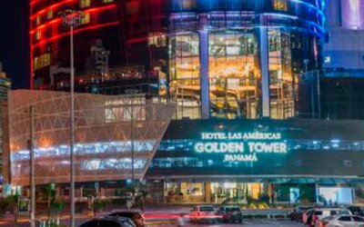 Night-time exterior of Hotel Las Américas Golden Tower Panamá, featuring illuminated glass architecture and colourful building lights.
