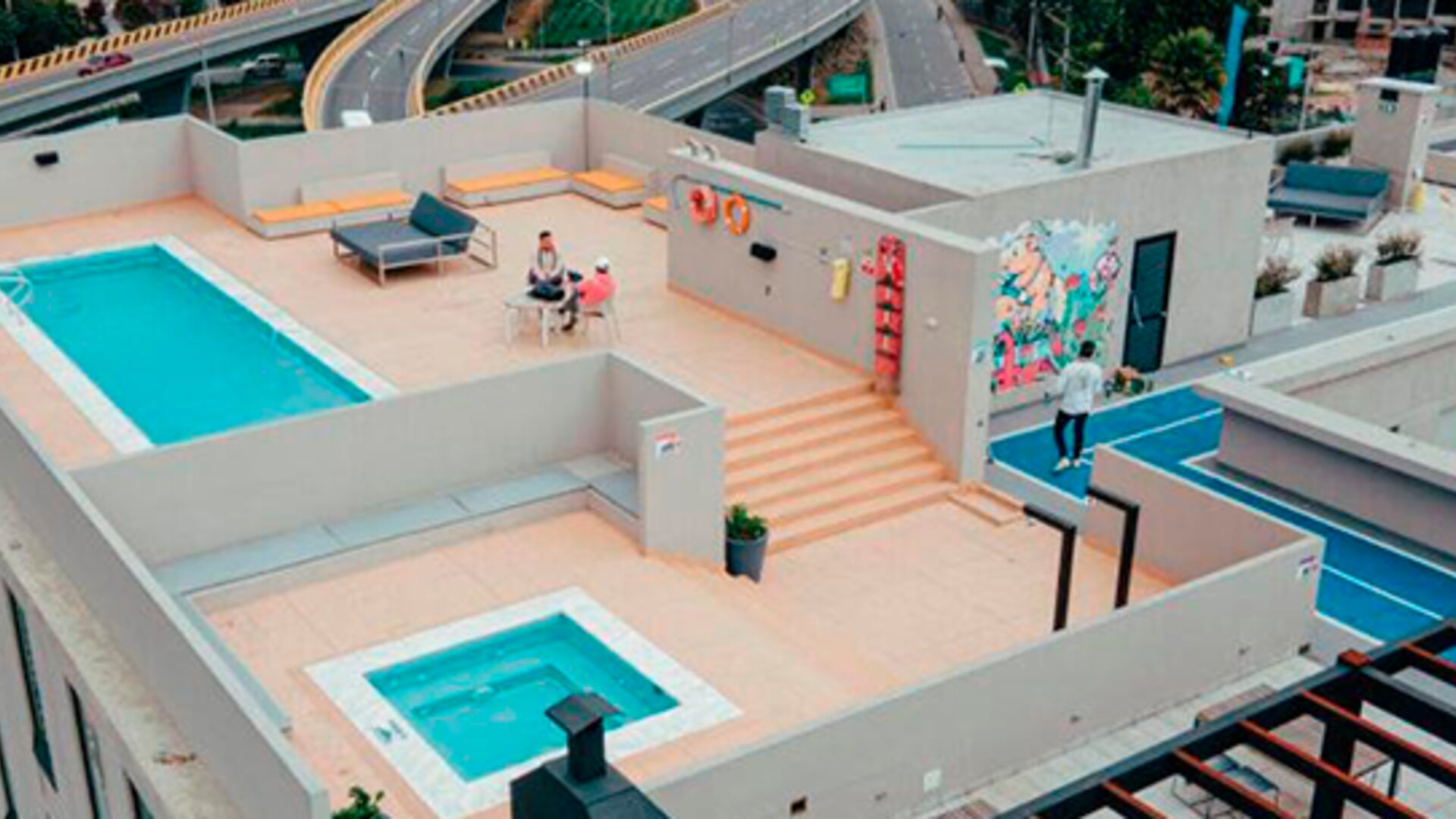 Aerial view of the rooftop terrace featuring a swimming pool, hot tub, seating areas and outdoor sports court at UMA Suites Chía.