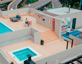 Aerial view of the rooftop terrace featuring a swimming pool, hot tub, seating areas and outdoor sports court at UMA Suites Chía.