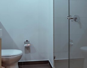 Bathroom with a glass-enclosed shower, white toilet and light wood vanity in a modern, minimalist interior at UMA Suites Chía.