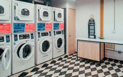 Laundry room with rows of stacked washing machines and dryers, folding space and ironing boards at UMA Suites Chía.