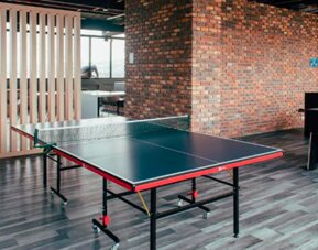 Recreation area with a table tennis table, foosball table, wooden slat partition and exposed brick walls at UMA Suites Chía.
