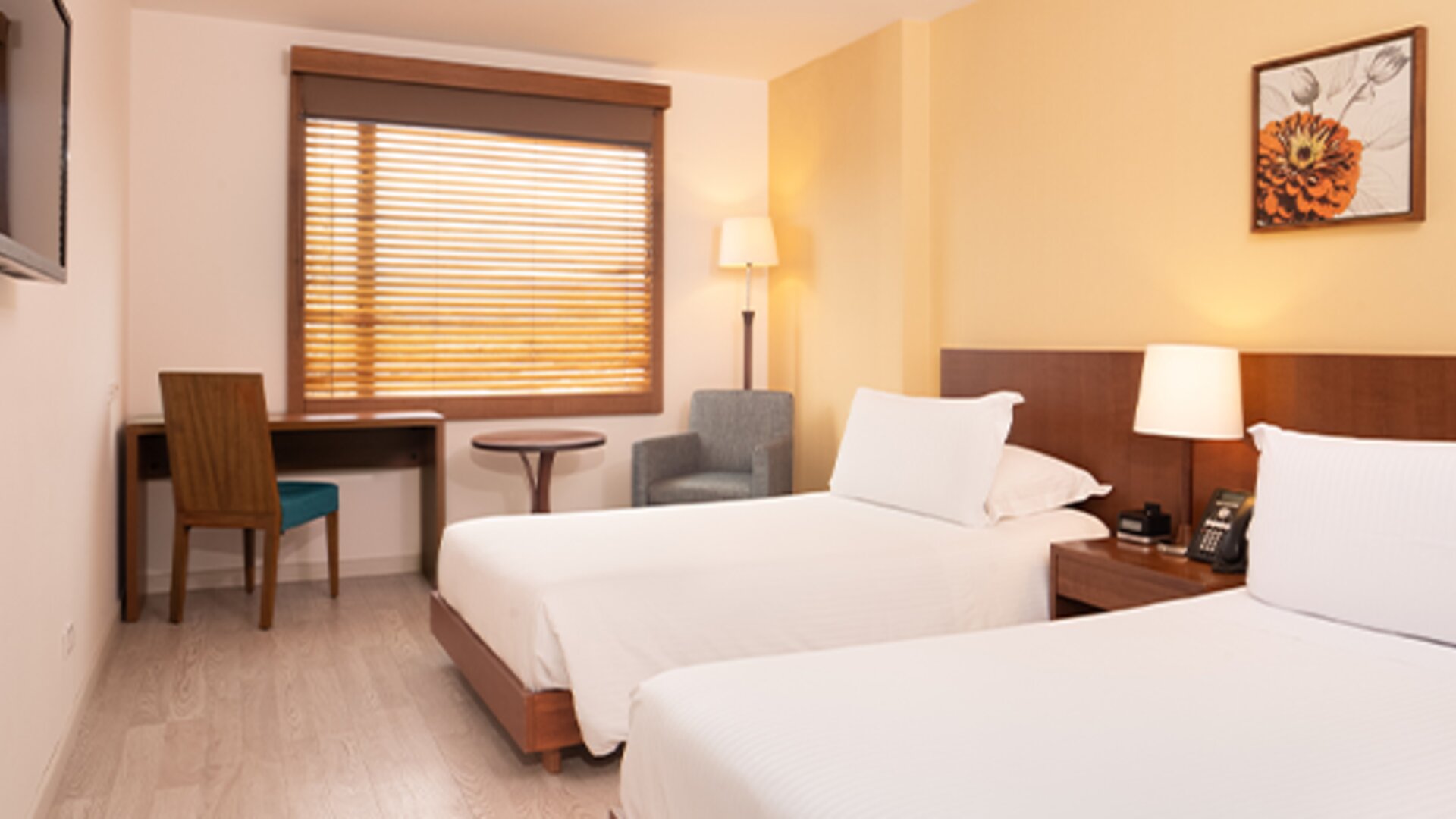 Twin guest room with white bedding, wooden bed frames, a desk, television and window blinds at Hotel Habitel Select.