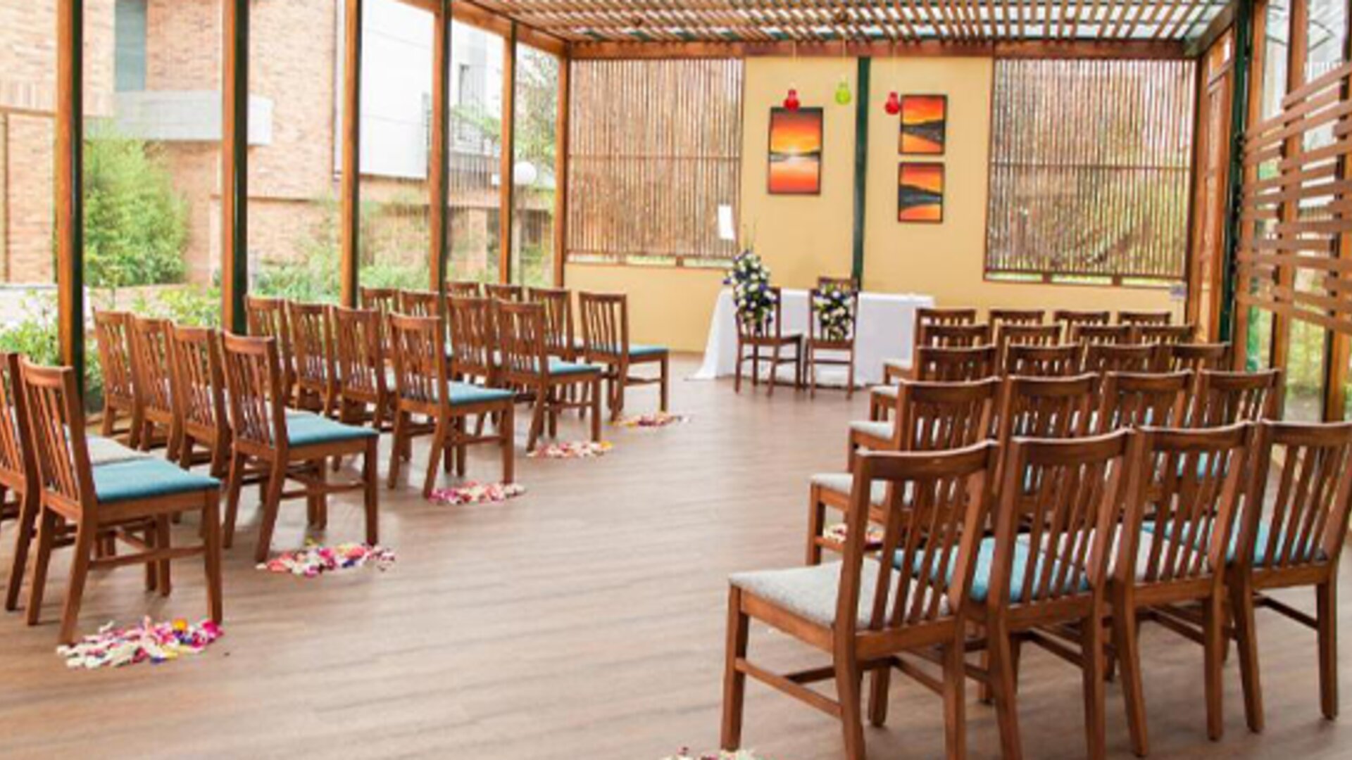 Outdoor dining or event space with rows of wooden chairs, a slatted timber canopy and surrounding greenery at Hotel Habitel Select.