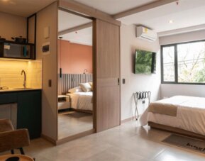 Studio-style guest room with a double bed, kitchenette, mirrored sliding wardrobe, air conditioning, and large windows at Hotel Living 35 Suites.