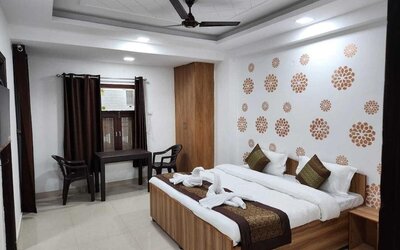 Guest room featuring a double bed with white bedding, red and gold accents, decorative towel arrangements, wooden furniture, a wardrobe, and a small table with two chairs at Hotel Urban Abode.