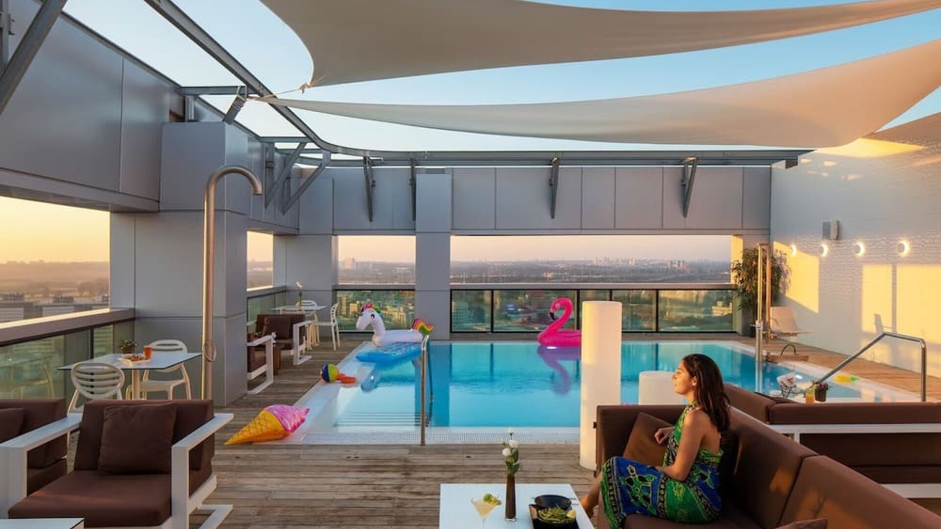 Rooftop pool with loungers, shaded seating, inflatable floats and city views at Prima Link.