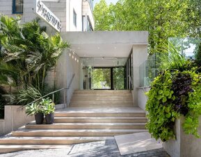 Hotel entrance with wide stone steps, glass doors and landscaped greenery at Prima Galil Tiberias.