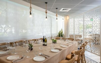 Private dining room with a long table, elegant table settings and wooden chairs at Prima Galil Tiberias.