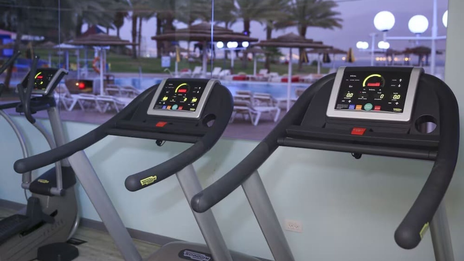 Fitness centre with treadmills overlooking the outdoor pool area at Prima Music Eilat.