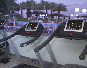 Fitness centre with treadmills overlooking the outdoor pool area at Prima Music Eilat.