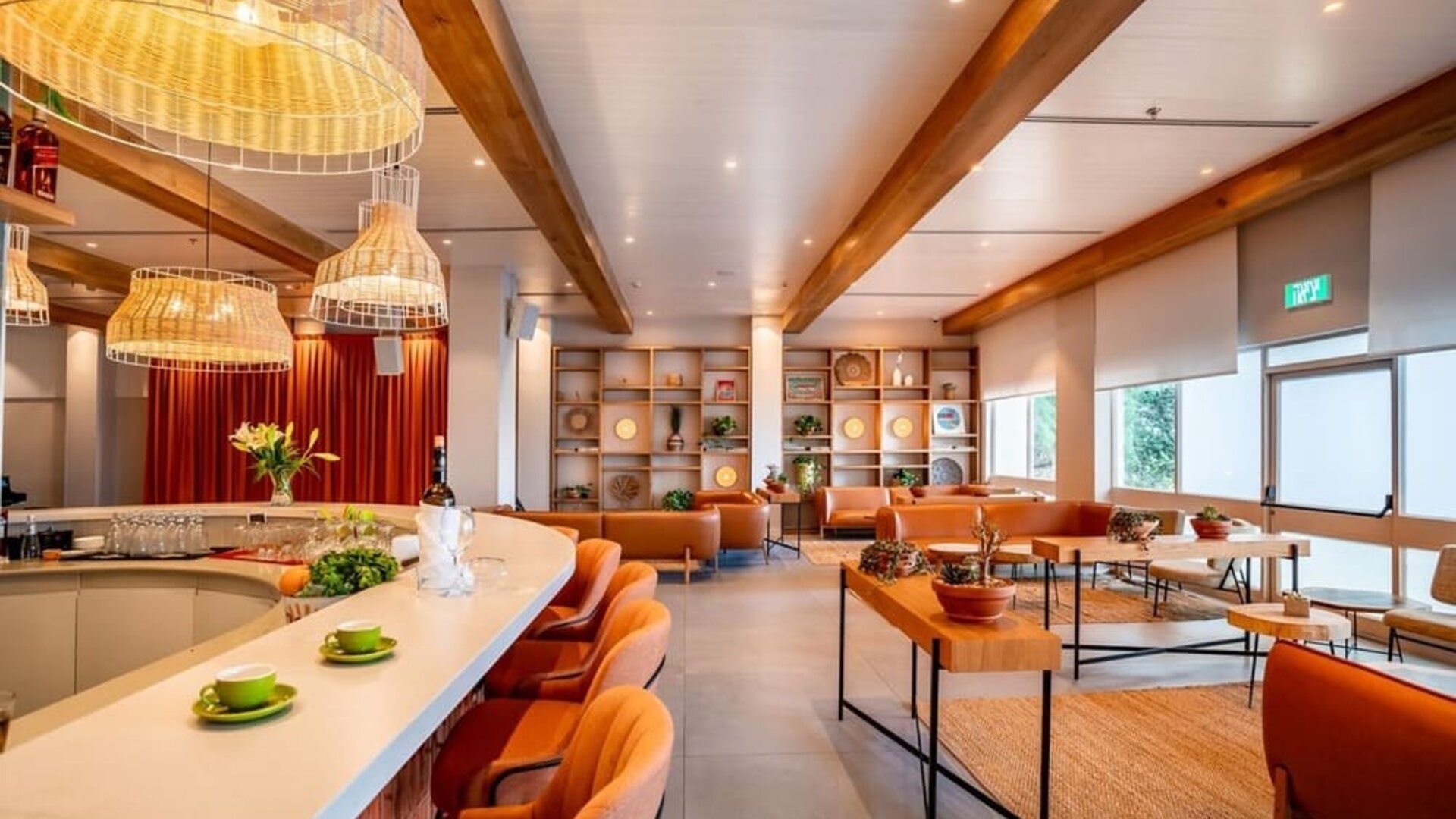 Restaurant and lounge area with orange bar stools, woven pendant lights, wooden ceiling beams and contemporary seating at Prima Music Eilat.