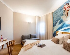 Guest bedroom with a double bed, white curtains and large windows providing natural light at Prima Music Eilat.