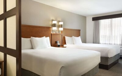 Guest room with two queen beds, white bedding and wooden privacy divider at Hyatt Place Portland Airport at Cascade Station.