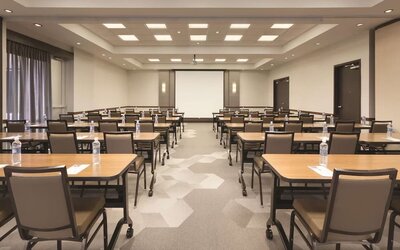 Meeting room with classroom-style seating, tables and presentation screen at Hyatt Place Portland Airport at Cascade Station.