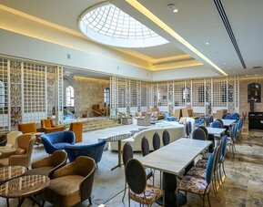 Dining area with tables, upholstered chairs and decorative lattice partitions at Lady Stern Hotel.