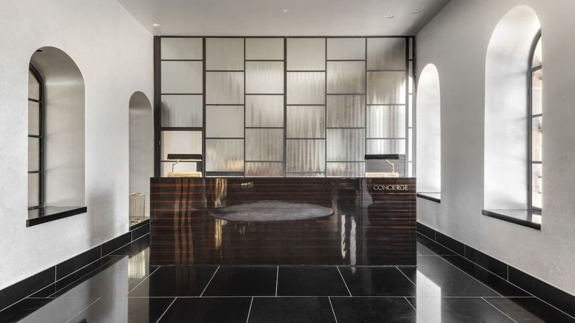 Lobby lounge with black tiled flooring, contemporary seating and gold decorative accents at Lady Stern Hotel.
