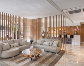 Lounge area featuring curved grey sofas, a round wooden coffee table and decorative timber screens at Hotel Sallés Ciutat del Prat.