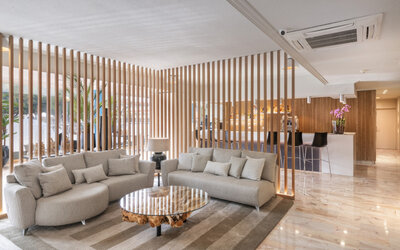 Lounge area featuring curved grey sofas, a round wooden coffee table and decorative timber screens at Hotel Sallés Ciutat del Prat.