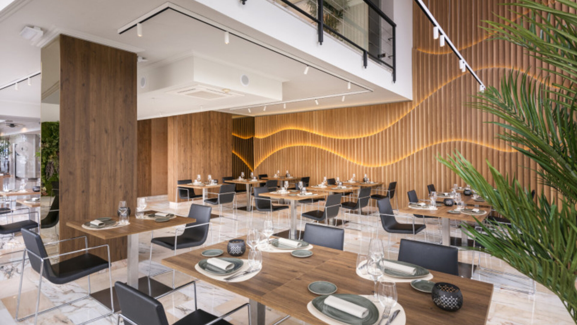 Restaurant seating with round tables, dark chairs and a circular vertical garden mounted on the wall at Hotel Sallés Ciutat del Prat.